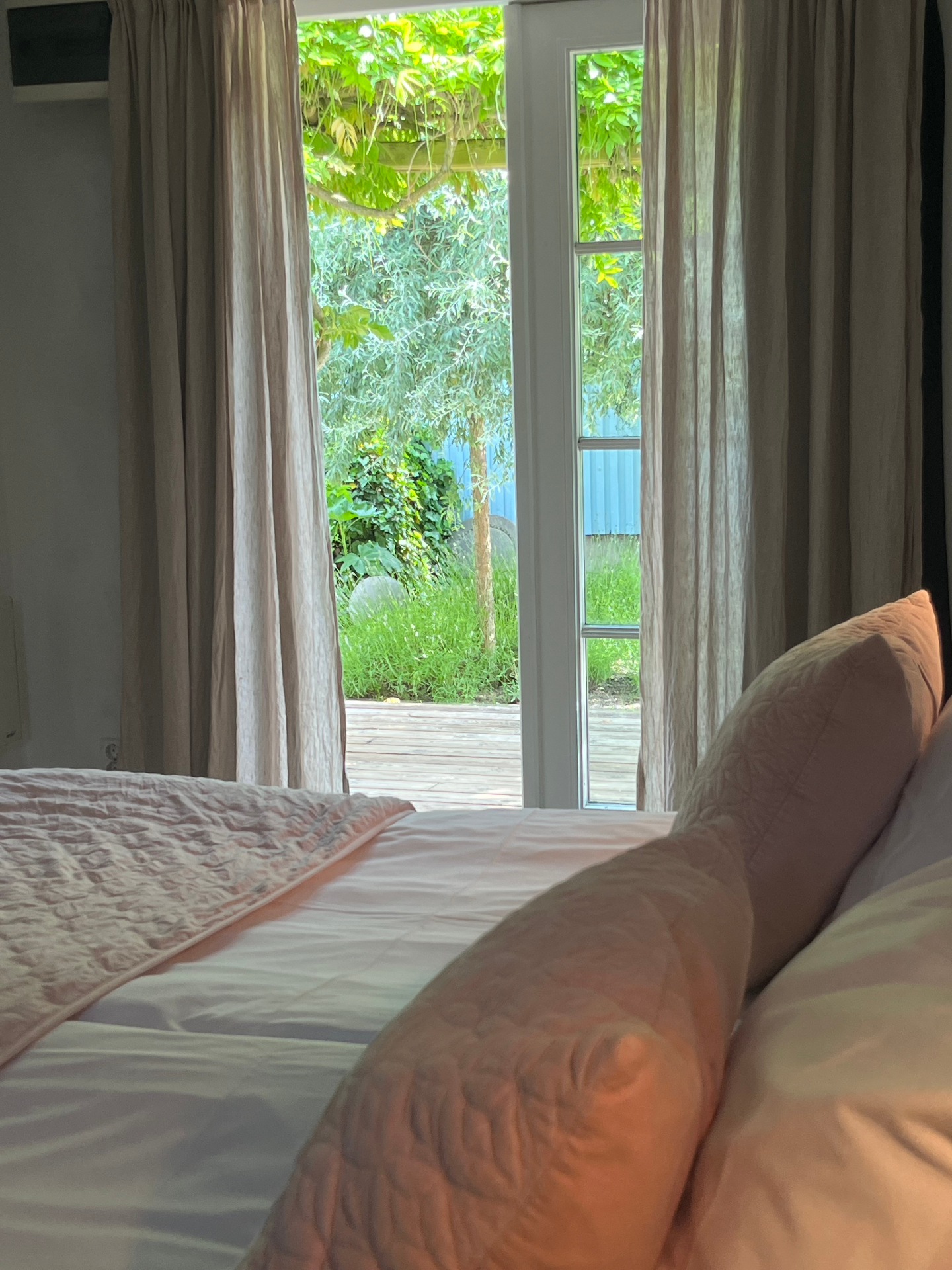 Hotellrum med dubbelsäng och linnetextilier i ljusa toner